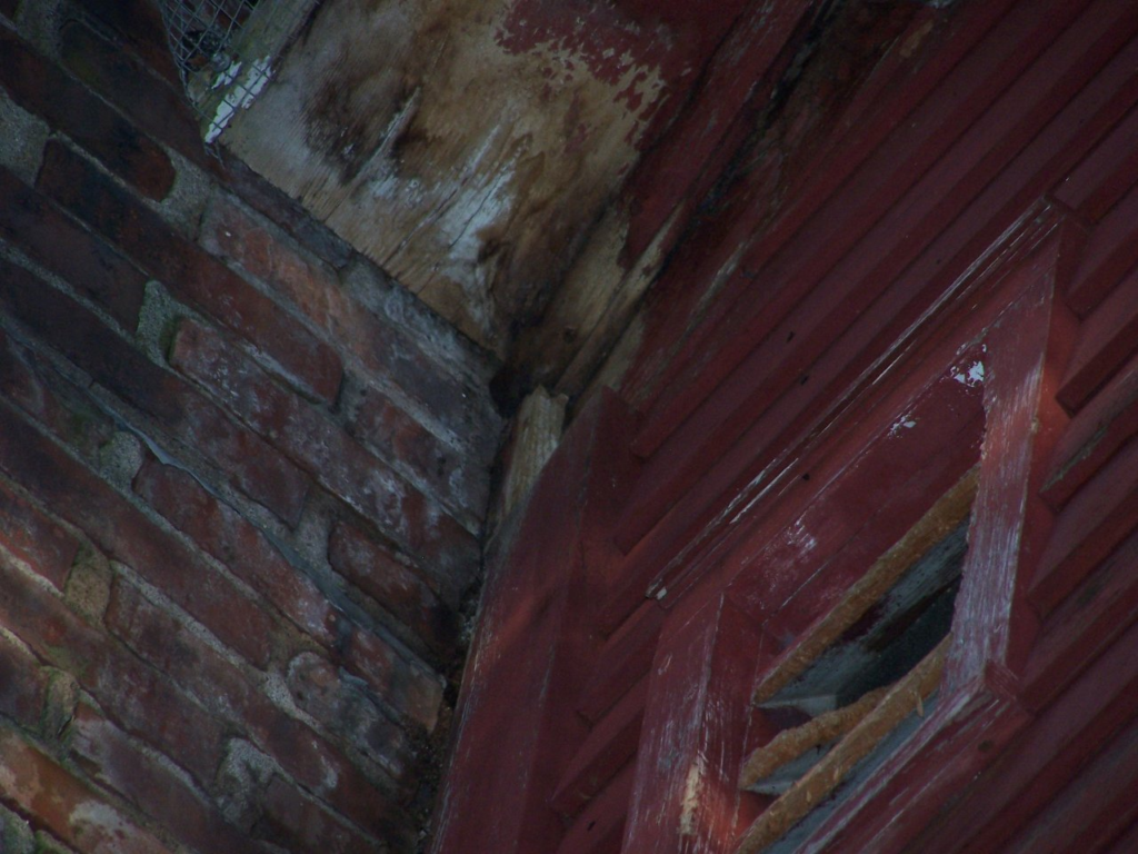 Damaged gable vent and water rot near a chimney allowing rodents access into the attic of a Connecticut home